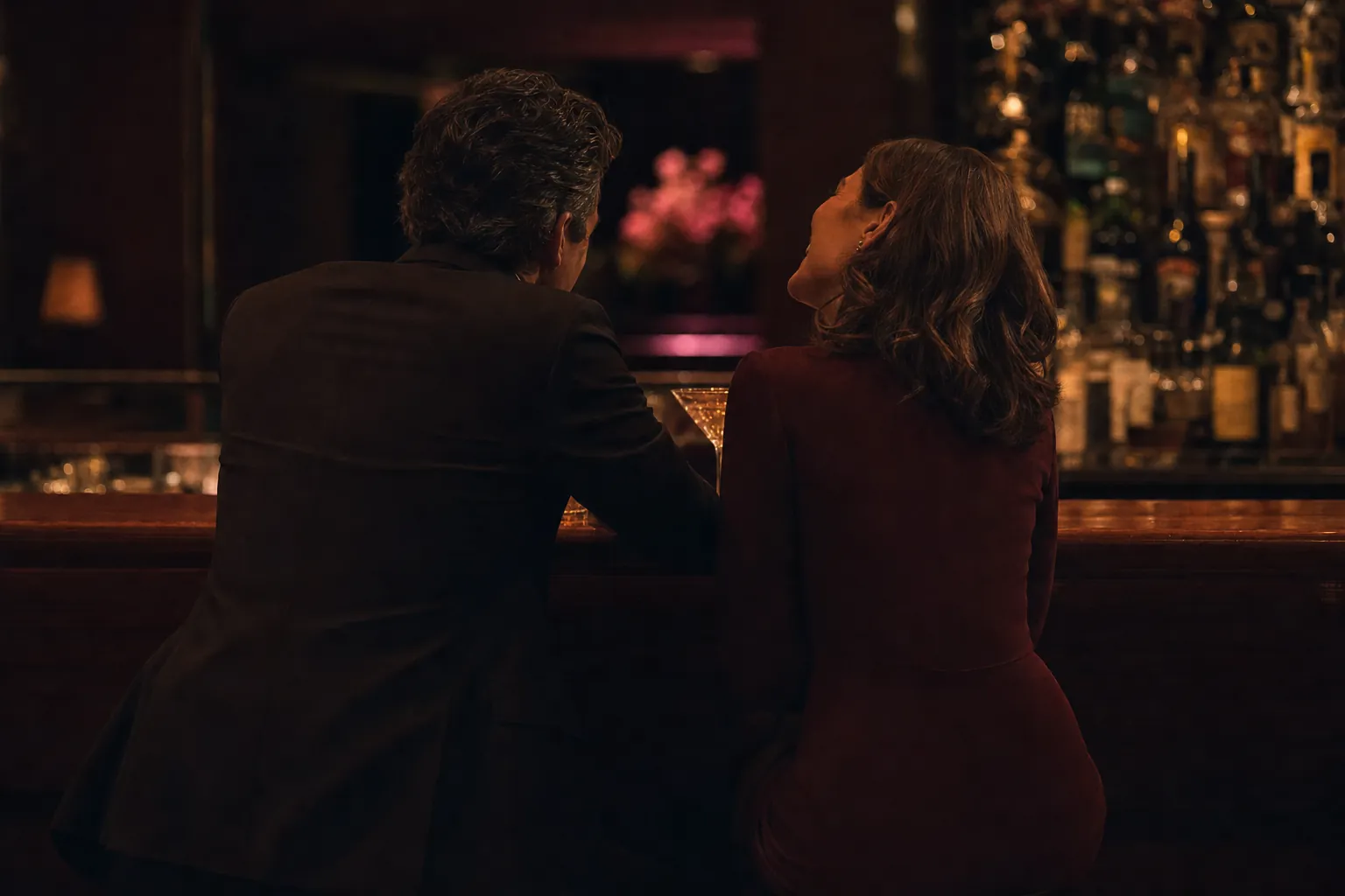 The same two people later in the evening, now sitting side by side at the bar, turned toward each other and laughing